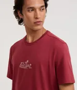 Remera de hombre color bordó, corte comfort, cuello redondo y manga corta. Presenta un pequeño estampado lineal minimalista en el pecho que simula un paisaje con palmeras y montañas.
