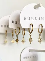 Aros de acero dorado con colgante de estrella, diseño moderno y elegante.