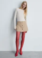 Minifalda color beige con cierre lateral y botones decorativos al frente.