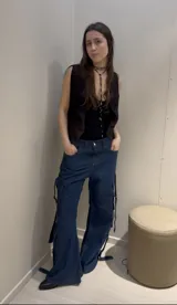 Pantalón cargo negro de denim rígido, corte wide leg, con bolsillos laterales y detalles de tiras con hebillas en los laterales.