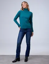 Polera de punto fino marca Nienty, color blanco, con cuello alto volcado y mangas largas con detalle de tajo en los puños.