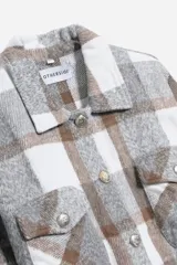 Chaqueta corta a cuadros grises, marrones y blancos, con cuello clásico, cierre abotonado, mangas largas y dos bolsillos con solapa en el pecho.