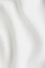 Buzo de punto fino color blanco, con escote amplio tipo barco que deja los hombros descubiertos, manga larga y puños y bajo acanalados.