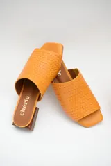 Zuecos color naranja con capellada tejida, taco bajo de madera y suela antideslizante.