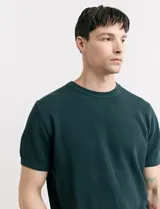 Remera de punto color verde oscuro, con cuello redondo y mangas cortas.