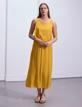 Vestido largo color mostaza de crepe, marca Marissa Olivia. Escote redondo con sobrecapa y detalle de crochet en los hombros. Corte en la cintura con punto smock. Sin mangas.