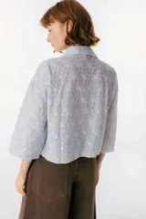 Camisa celeste a rayas verticales blancas con bordado de flores blancas, de mangas 3/4 y corte recto.