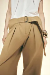 Pantalón color beige de tiro alto con cinturón ajustable con hebilla metálica. Presenta bolsillos laterales, de vivo en la pierna y de parche en la espalda.