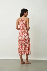Vestido midi con estampado abstracto en tonos naranja y blanco, breteles finos y corte evasé.
