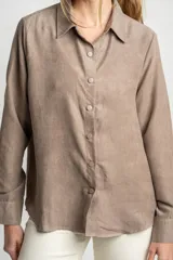 Camisa color marrón claro de gamuza vegana con calce oversize, cuello clásico, cierre frontal con botones y mangas largas con puños abotonados.
