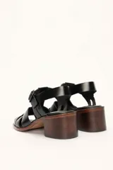 Sandalias plateadas de cuero con tiras entrecruzadas y hebilla lateral. Taco de madera de 6 cm.