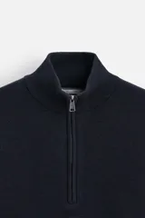 Jersey azul marino de punto suave, corte regular, cuello alto con cremallera frontal, manga larga y terminaciones en rib.