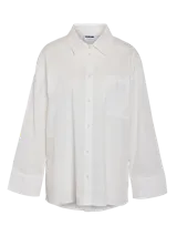 Camisa blanca de corte holgado, manga larga con puños anchos y bolsillo en el pecho.
