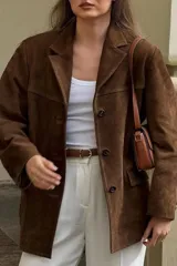 Blazer marrón de gamuza con cuello de solapa, cierre con botones y bolsillos frontales.