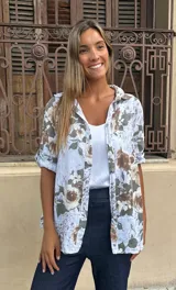 Camisa de algodón blanca con estampado floral en tonos tierra y verde oliva, manga corta y cuello camisero.