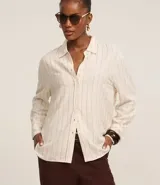 Camisa de viscosa y lino color crudo con finas rayas verticales azules, cuello clásico, mangas largas con puños abotonados y cierre frontal con botones.