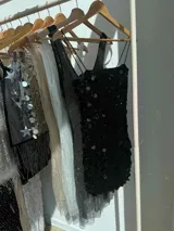 Vestido corto negro con lentejuelas de distintos tamaños, tirantes finos elastizados y cierre en la espalda.