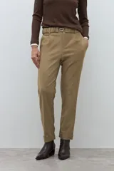 Pantalón negro de vestir, corte recto y tiro alto, con pliegues frontales y puños doblados. Se complementa con un cinturón fino negro con hebilla metálica en forma de símbolo.