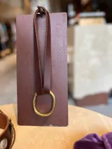 Gargantilla de cuero marrón con aro grande de bronce.