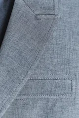 Blazer azul con cuello solapa y manga larga. Tiene un bolsillo de vivo en el pecho y cierre frontal con botones ocultos.