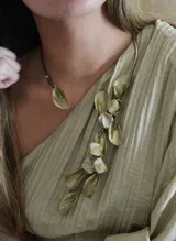 Gargantilla de bronce con dije de hoja y collar con dije de hojas y piedras de nácar.