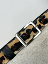 Cinturón de cuero con estampado animal print, hebilla cuadrada plateada y reverso negro.