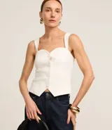 Blusa blanca de tejido plano en sastrería, con escote corazón, breteles anchos, botones forrados, elástico en la espalda y bajo con recorte V.