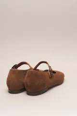 Zapato estilo Mary Jane color marrón, de cuero, con punta redondeada y tira sobre el empeine con hebilla.