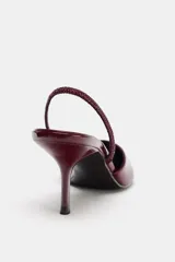 Zapato destalonado de charol negro con escote en pico, tira trasera ajustable y tacón fino.