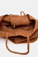 Bolso tipo maxi shopper color marrón, confeccionado en ante. Tiene doble asa de hombro y bolsillo interior con cremallera.