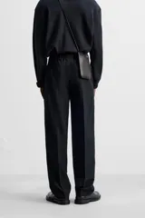 Pantalón de vestir negro de corte recto, con cintura elástica, pliegues frontales, bolsillos laterales y traseros.