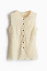 Chaleco color crema de punto texturizado con cuello redondo y botones frontales.