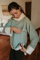 Sweater tejido color crema con cuello alto y mangas largas. Tiene corte oversize y aberturas laterales con cierres invisibles verticales para amamantar.