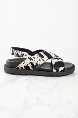 Sandalias con tiras cruzadas de cuero con estampado animal print de vaca en blanco y negro.