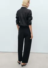 Pantalón negro de corte recto, tiro medio y cintura elástica.
