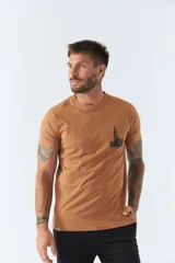 Remera color caramelo de corte clásico, con cuello redondo y manga corta. Estampa pequeña en el pecho con el dibujo de un edificio y la inscripción "BROOKSFIELD".