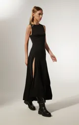 Vestido negro sin mangas de poliéster, corte al cuerpo, largo midi con abertura lateral y cuello redondo.
