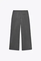 Pantalón de tiro alto negro a rayas verticales blancas, con cintura elástica ajustable con cordones, bolsillos delanteros y banda lateral blanca.