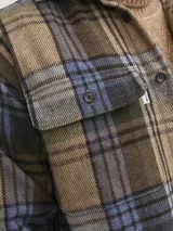 Sobrecamisa de manga larga a cuadros en tonos marrón, azul y verde. Tiene cierre con botones, bolsillos en el pecho con cierre de botón y corte relajado.