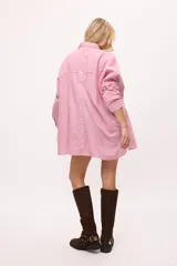 Camisa oversize a rayas verticales color amarillo y blanco, con cuello camisero, manga larga y cierre frontal con botones.