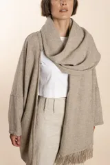 Saco de lana color marrón claro, con mangas amplias, cuello tipo bufanda con flecos y bolsillos laterales. Diseño oversize sin forro.