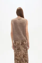 Chaleco de tejido de punto acanalado, color marrón claro jaspeado, sin mangas y con cierre frontal de botones pequeños.