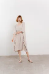 Vestido midi de lino con corte relajado y silueta fluida. Presenta escote redondo, mangas 3/4 y bolsillos laterales. Diseño minimalista y atemporal ideal para el verano.