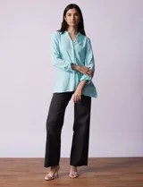 Camisa celeste texturada con cuello con solapa y abertura central con botones. Delantera con bolsillo aplicado y largo de manga regulable con presilla y botón.