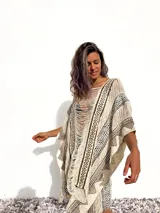 Poncho de tejido rústico color crudo con estampado geométrico en marrón y flecos.