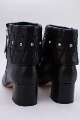 Botas cortas color peltre con taco cuadrado, capellada de cuero y cuello con diseño capitoné y apliques brillantes.