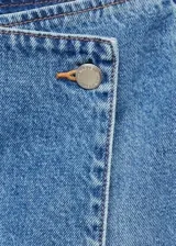 Short pollera de jean de tiro medio con diseño cruzado y cierre de botón.