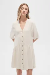 Vestido corto color crema, de corte holgado, con cuello en V y botones frontales.