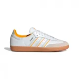 Championes Adidas Samba OG de cuero blanco con detalles en naranja y suela de goma marrón.