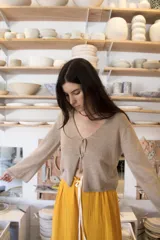 Blusa de punto color beige, de corte recto y escote en V con detalle de nudo.